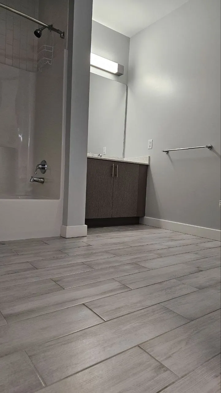An empty bathroom with a bathtub, grey walls and a clean floor