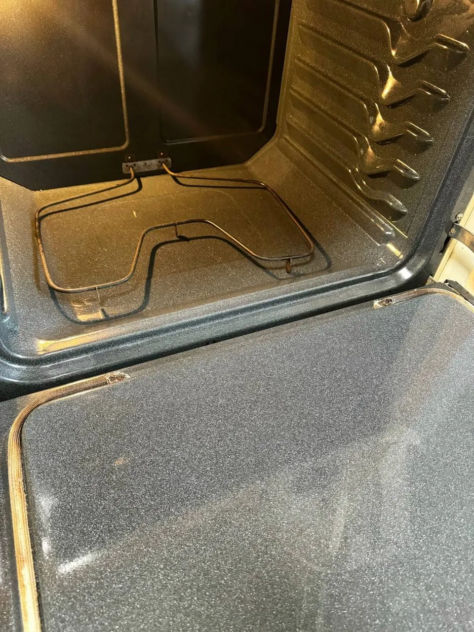 Inside of an oven with dark burnt-on spots, before cleaning